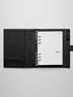 Image shows the 2026 front cover used in a black leather A5 ring-bound planner.
