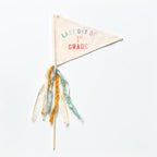 A collection of flag trimmings displayed on sticks, with a variety of colors and decorative elements such as ribbons and feathers.