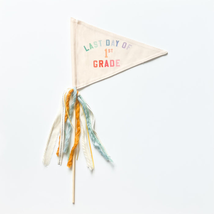 A collection of flag trimmings displayed on sticks, with a variety of colors and decorative elements such as ribbons and feathers.