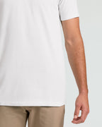 Close-up of a person wearing a plain white short-sleeve T-shirt with beige pants, shown against a light gray studio background.