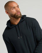 Man wearing Black Waffle Hoodie with kangaroo pocket, against gray background.