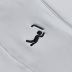 A close-up of the Bone - Q-Zip’s white, athletic-fit fabric showcases a small black embroidered stick figure lifting a bent bar. Diagonal stitching at the edges highlights both its durability and stylish design.