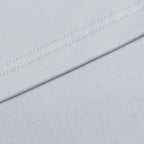 Close-up of the Bone Q-Zip’s light gray, athletic fit fabric with a smooth texture and neat stitching. Slight folds form a diagonal line, highlighting the Q-Zip’s moisture-wicking properties against a softly textured background.