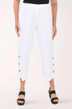 White pants with gold buttons worn by a person on a white background
