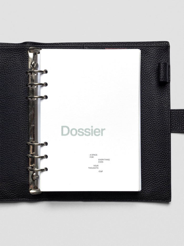 White cardstock planner dashboard with "Dossier" text in a green-blue flocked material with text below in A5 size shown in a leather planner cover.