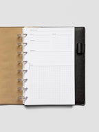 Meeting notes insert displayed in a black leather planner with tan interior. The minimal layout features sections for subject, agenda, attendees, follow-up, and a gridded notes area.