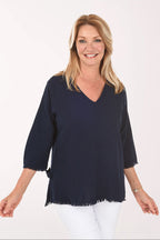 Woman wearing a navy blue blouse with white pants on a white background