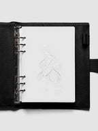 Light grey, semi-transparent, and glossy plastic planner dashboard with organic raised shape design in size A5 shown ringbound in a black leather agenda.