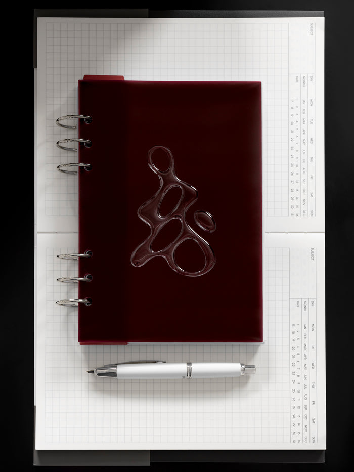 Gloss Form Planner Dashboard | Bordeaux shown ringbound in size A5 on an open notebook.