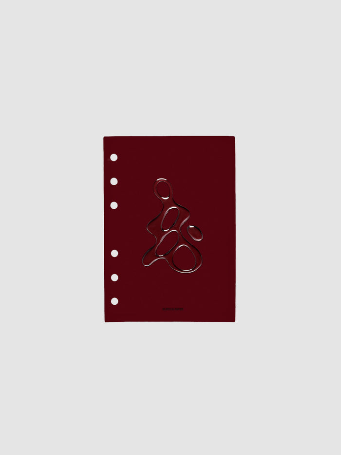 Dark red, semi-transparent, and glossy plastic planner dashboard with organic raised shape design in size A6 on a neutral background.