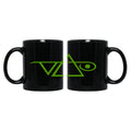 Image of a black coffee mug against white background. the mug has the steve vai logo in it in green.  The steve vai logo makes the word "vai" with an upside down triangle, a right side up one, and a line going across the triangles with a curl at the end next to the triangle that is upright.