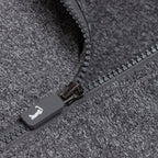 Close-up of the Heather Gray - Q-Zip, featuring an athletic fit with a partially unzipped gray zipper on dark heathered fabric. The gray pull displays a white animal icon, and both the zipper teeth and fabric texture are clearly visible.