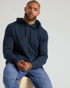 Man wearing Heather Gray & Navy Waffle Hoodie, seated, showing hoodie features.