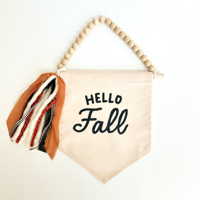 Fabric banner with 'Hello Fall' text and wooden beads on a white background