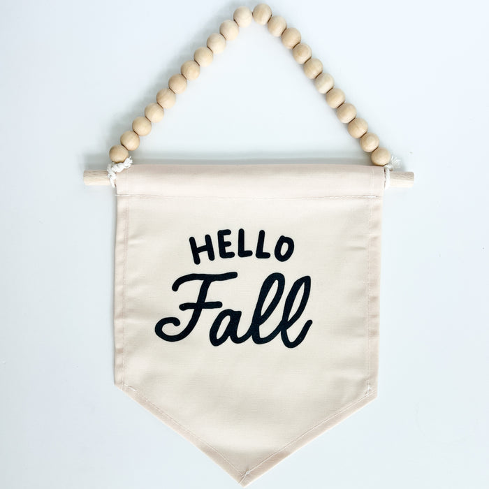 Fabric banner with 'Hello Fall' text and wooden beads on a white background