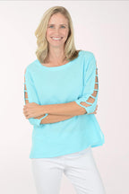 Woman wearing a light blue top with sheer sleeves on a white background