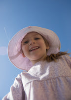 Wearing a bright yellow leopard print long-sleeved dress for children with elastic in the sleeves and a snap closure at the back, along with a matching sunhat.