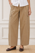 Close-up crop of a model wearing the Aspiga Matcha Trousers in Camel with a white blouse, showing the cargo pocket