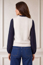 Model wearing the Aspiga Merino Wool Knitted Short Tank in Ivory over a navy lace blouse with jeans, back view