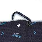 A black carabiner with BOESHIELD in white is attached to the Natural Slice - Towel, a dark microfiber towel with blue and white arrow patterns and "Natural Slice" printed on both sides for style and visibility.