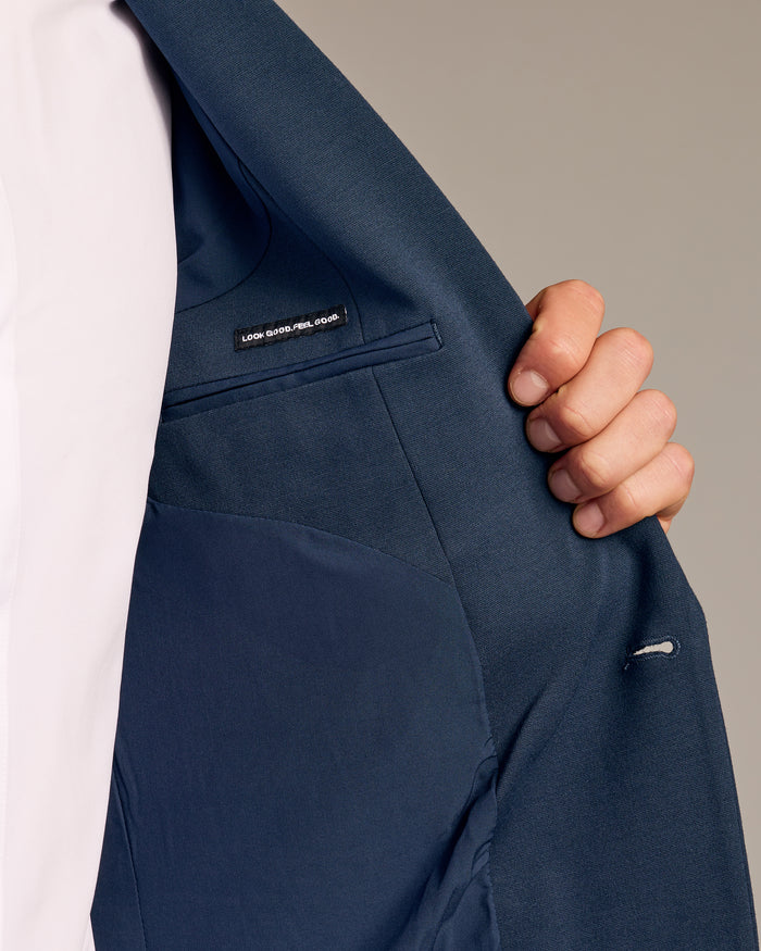Person holding open Navy Comfort Knit Blazer, showing interior lining and label.
