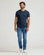 Man wearing a navy crew neck t-shirt with curved hem paired with blue jeans and white sneakers, showcasing the Pima Cotton Blend Curved Hem Crew 4-Pack men's basics.
