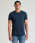 Man wearing a navy Tall Pima Cotton Blend Curved Hem Crew 4-Pack t-shirt paired with light blue jeans, showcasing a clean, fitted men's basics style.