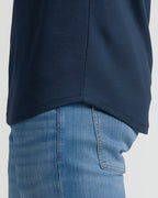 Close-up of the curved hem detail on the Navy Tall Pima Cotton Blend Curved Hem Crew worn over light blue denim jeans, highlighting the smooth fabric and tailored fit.