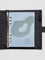 Textured blue planner dashboard with organic shape design flocked in blue-green with text shown in A5 size inside a leather planner cover.