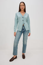 Longline cardigan in a cotton-wool blend in Stone Blue Colorway. The design features drop shoulders and a front cutaway detail, creating a soft, relaxed, and flattering silhouette. Full Body Front View on Model.