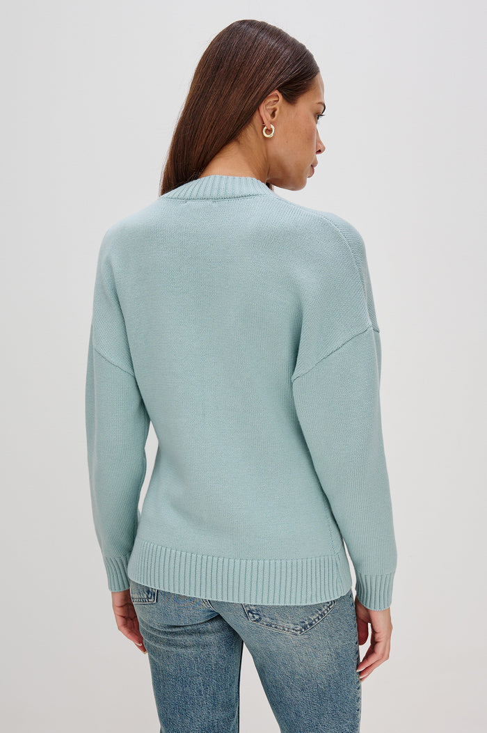 Longline cardigan in a cotton-wool blend in Stone Blue Colorway. The design features drop shoulders and a front cutaway detail, creating a soft, relaxed, and flattering silhouette. Back View on Model.