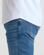 Detail close-up of a white Pima Cotton Blend Curved Hem Crew 7-Pack shirt worn untucked over blue jeans, highlighting the curved hem design and fabric texture.