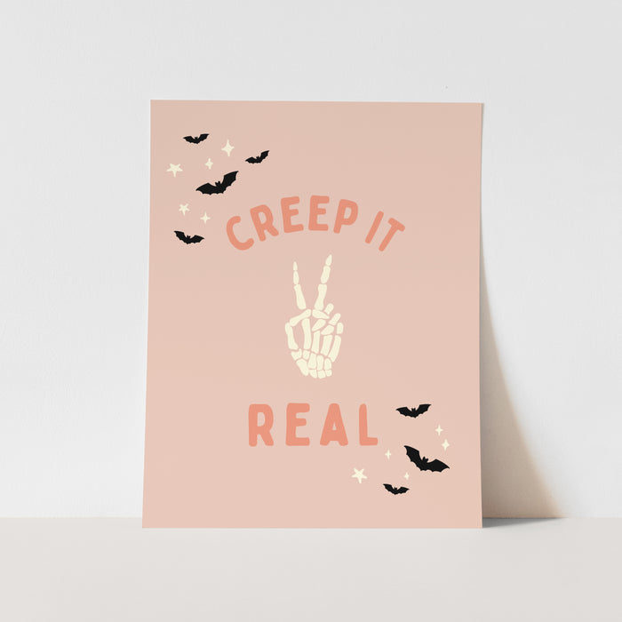 Poster with 'Creep It Real' text and skeleton hand design on a pink background