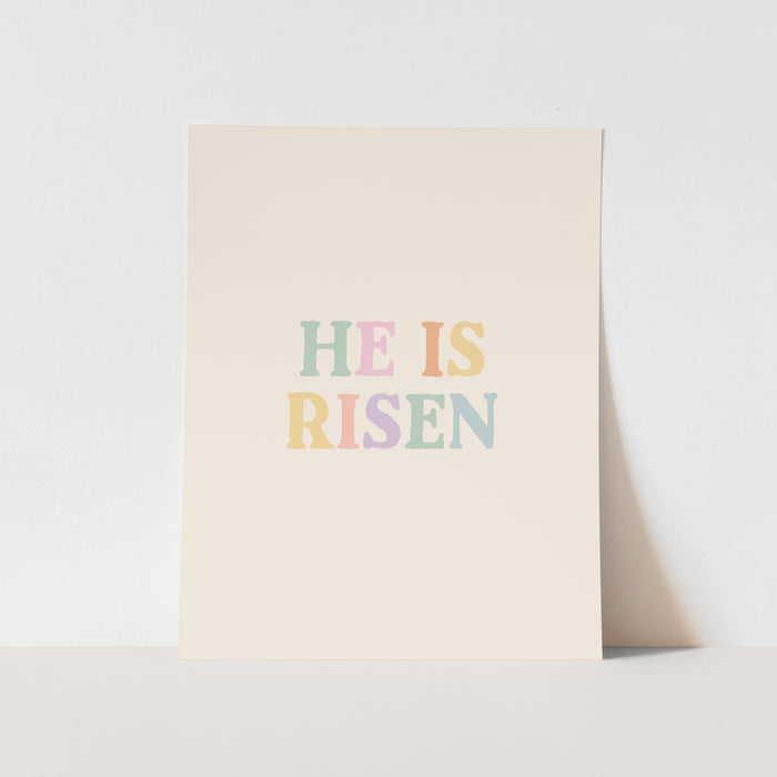 Poster with 'HE IS RISEN' text in pastel colors on a light background