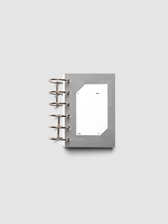 Grey cardstock planner dashboard with white plastic card inserted in slits with white printed text shown in size Pocket shown in a ring bound planner.