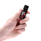 A person's hand is holding the small, dark brown dropper bottle of Spanish Fly Red Hot.