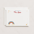 A stack of white flat note cards with a rainbow and stars design, personalized with the name 'Mrs. Lewis' at the top, and an envelope.