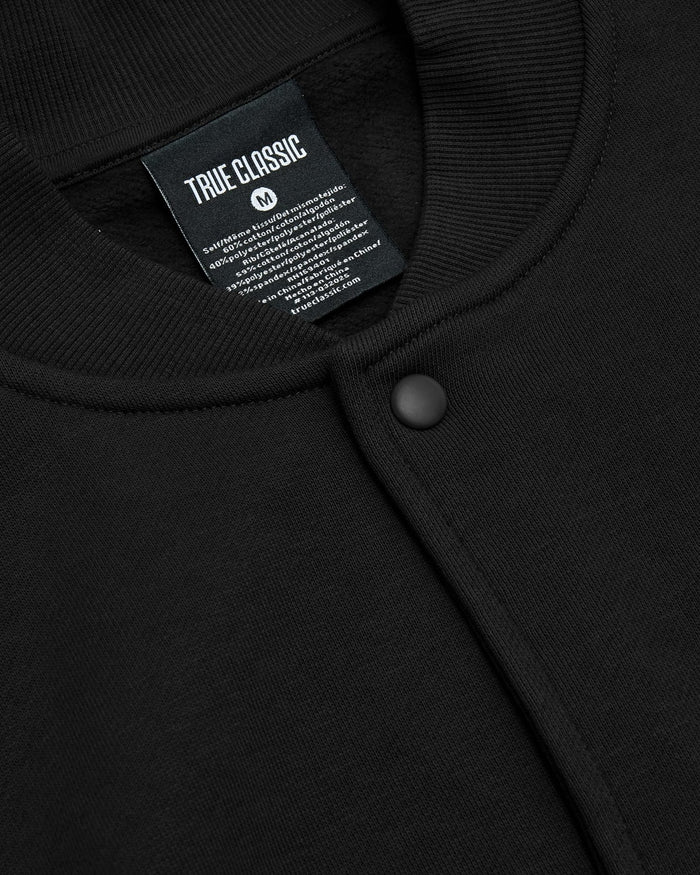 Black Fleece Bomber Jacket, close-up of collar, snap-buttons, TRUE CLASSIC tag.
