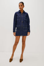 The Trabuco is a collared two-way zip front jacket with two chest pockets and a western style yoke in Deep Indigo colorway - a rinse denim wash. Front full body view featured on model.