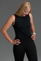 Woman wearing a black sleeveless top and leggings against a gray background || Black